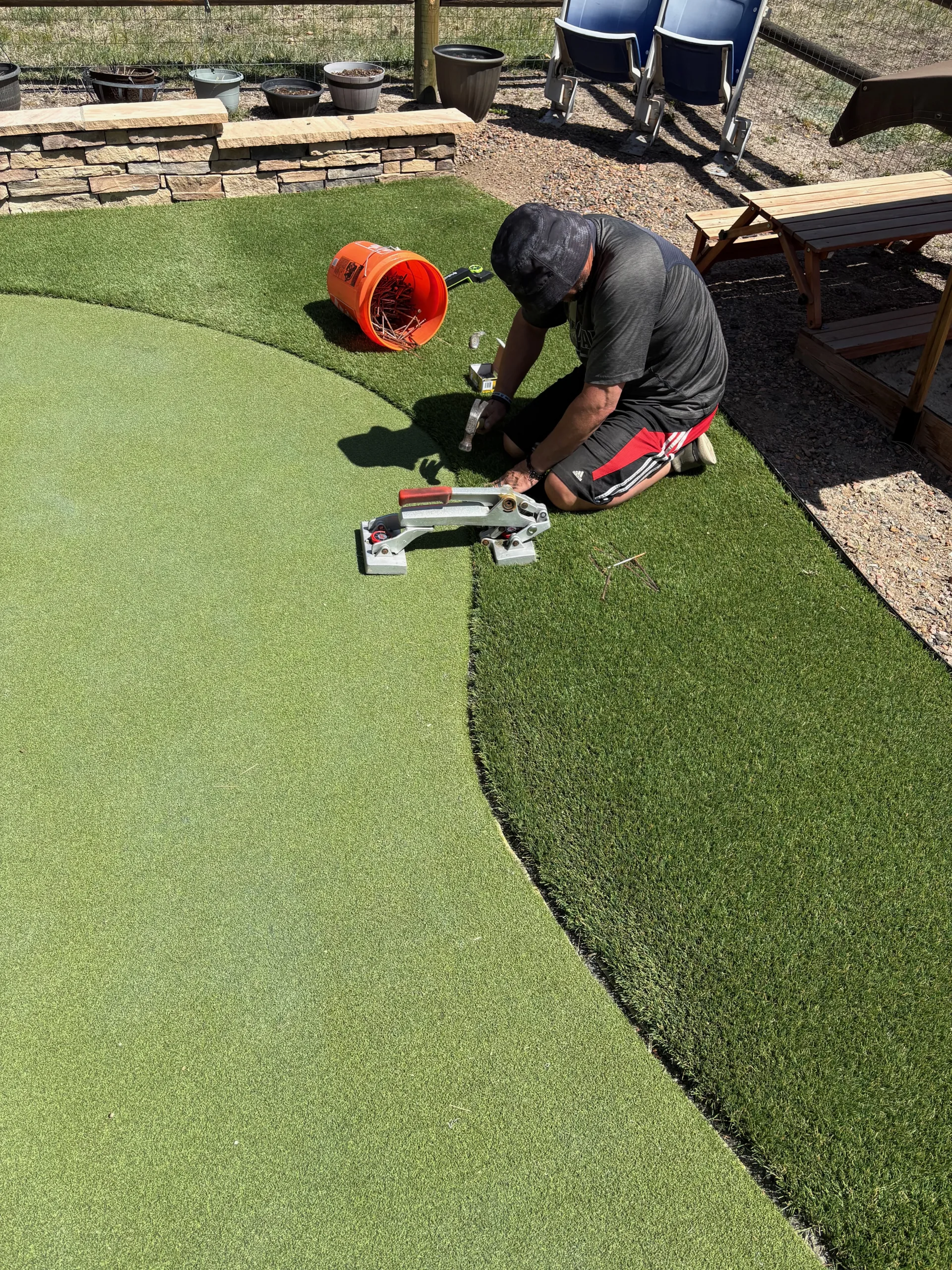 Technician seaming the curved edge of a residential putting green